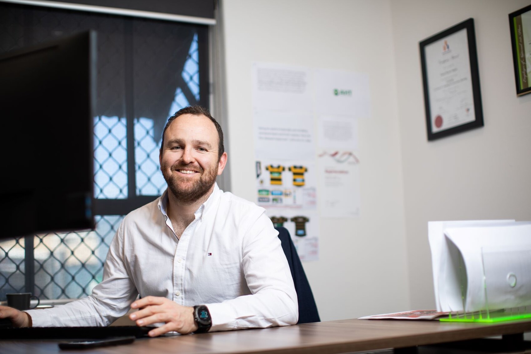 Man behind desk on computer smiling